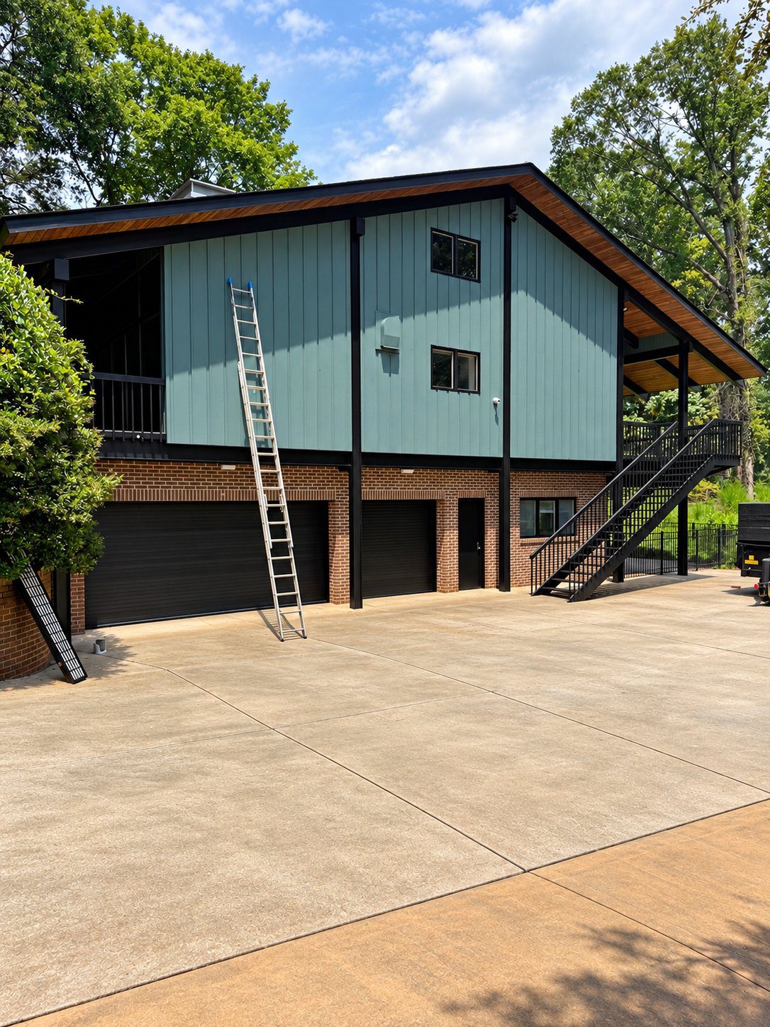 Sage green board-and-batten siding with black trim and brick base, exterior house painting by Verdeja Painting