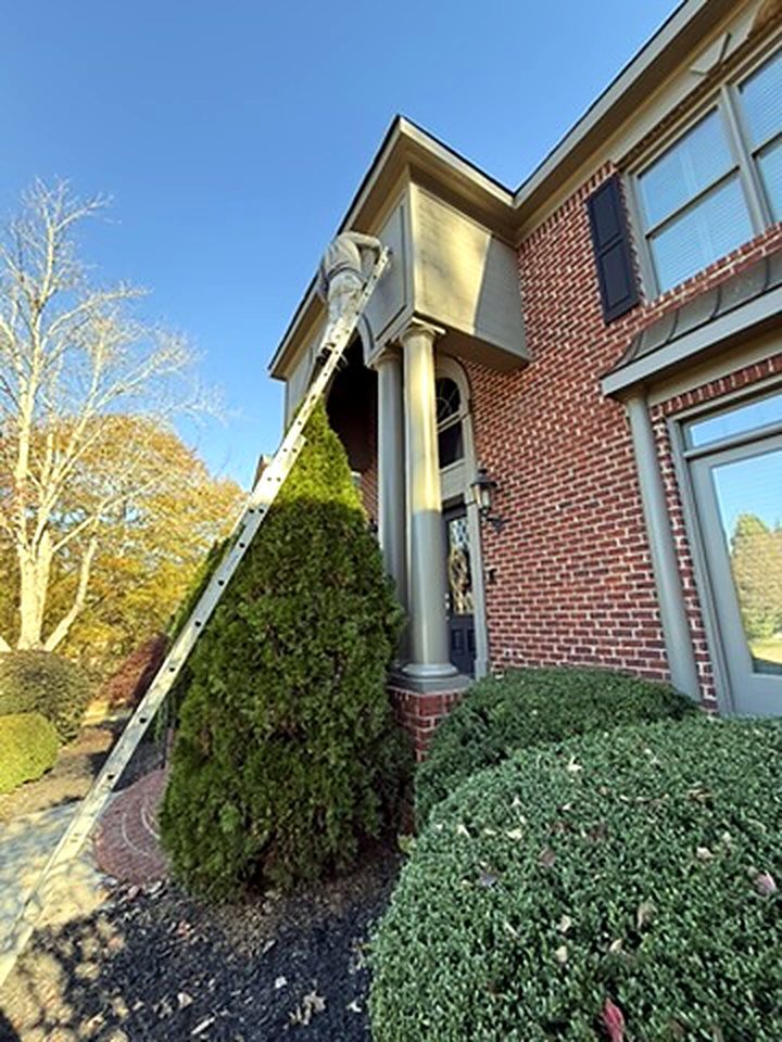 Painter on a ladder painting exterior trim on a brick home, exterior painting Five Forks SC