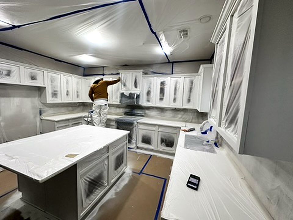 Painter spraying kitchen cabinets with the kitchen fully masked, cabinet painting Five Forks SC