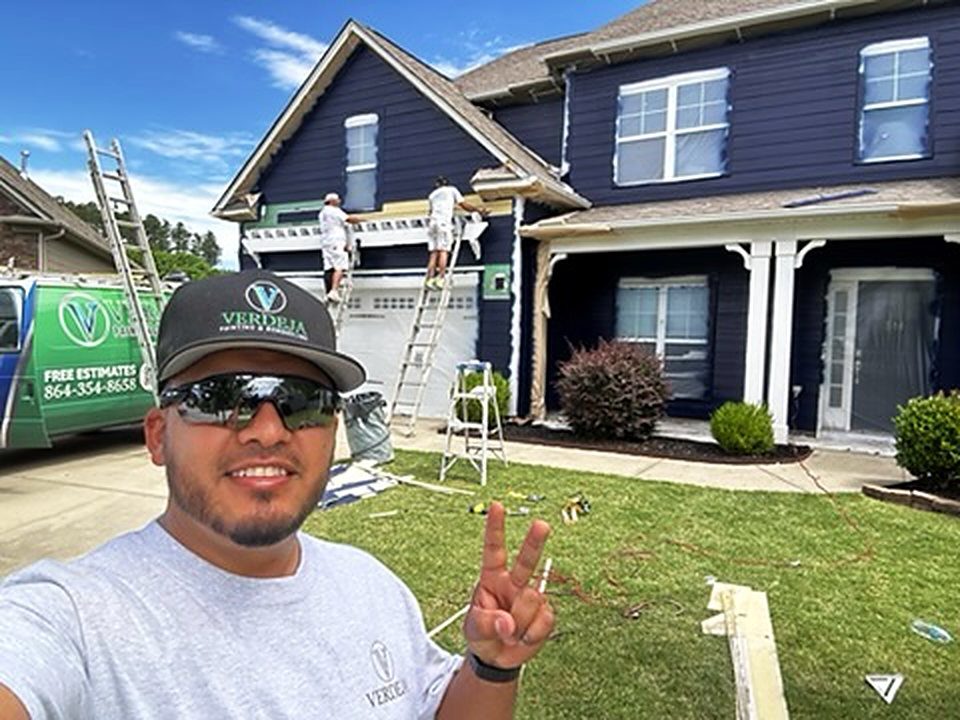 Tony Verdeja with his crew painting a navy blue house exterior in Greenville SC